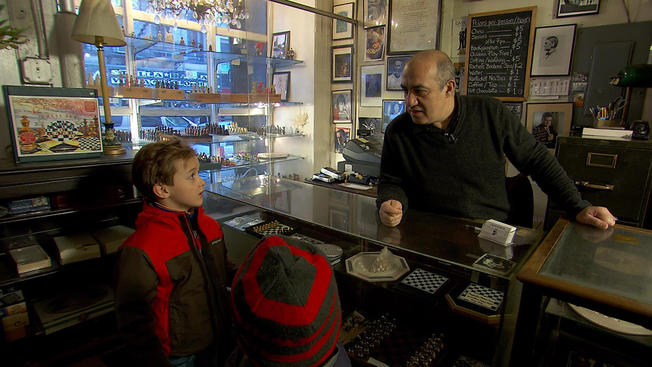 Chess Forum owner Imad Khachan talks shop with Oliver Armstrong, 8 and his brother Henry, 6.